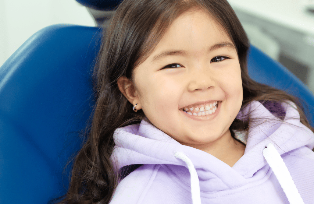 Criança sorrindo e feliz na cadeira do dentista