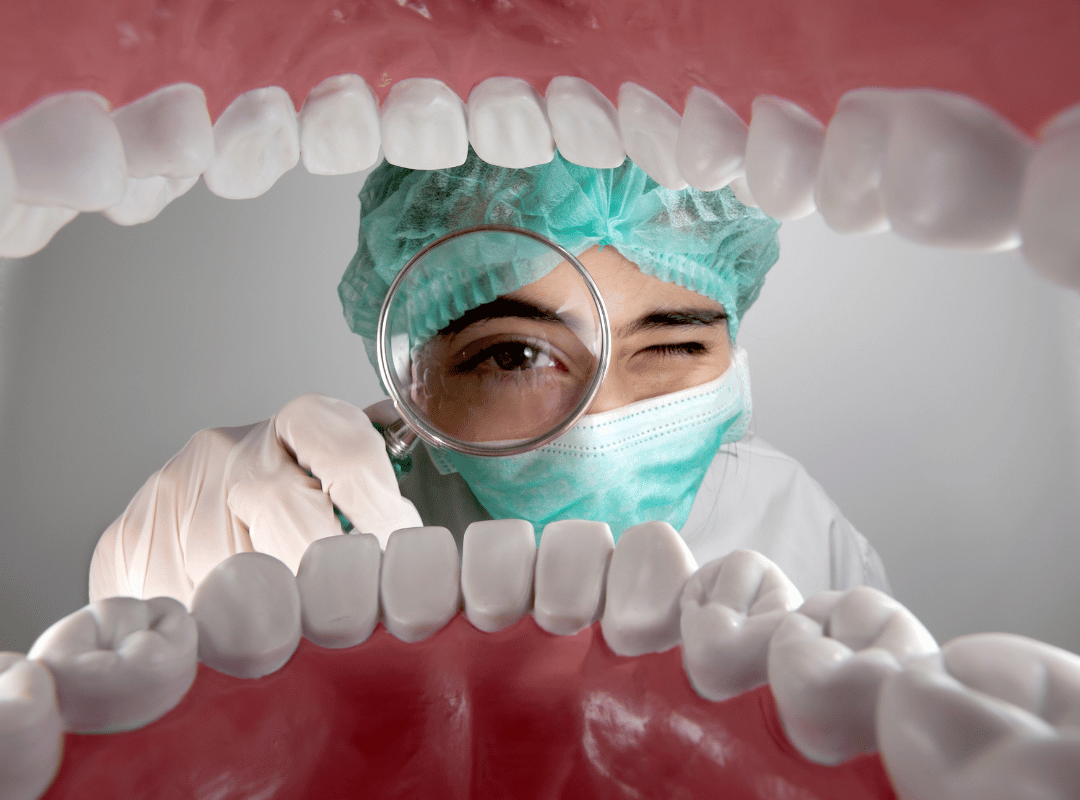 Dentista com lupa olhando os dentes de um paciente.